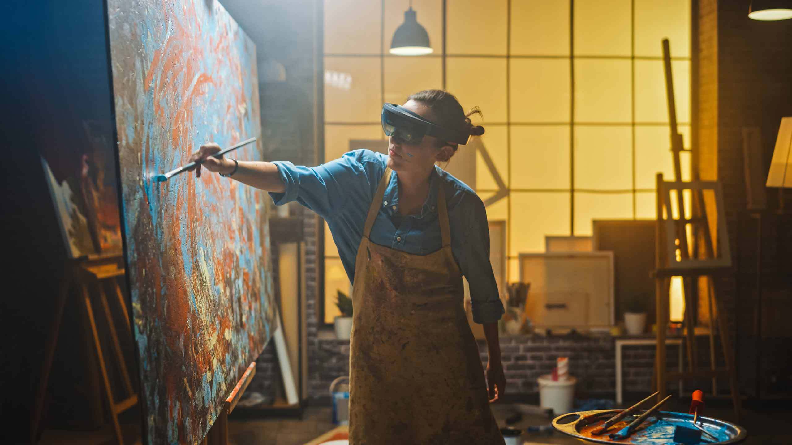 Künstlerin malt auf Leinwand und hat dabei eine Augmented Reality Brille auf